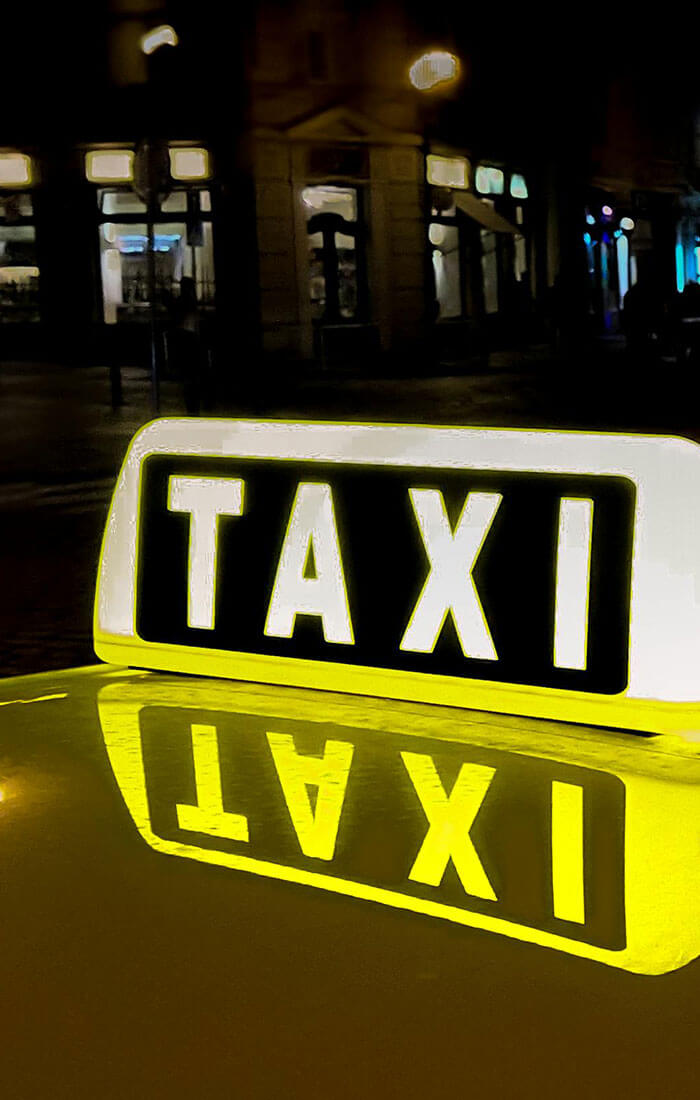 ein leuchtendes Taxischild auf einem Fahrzeug bei Nacht
