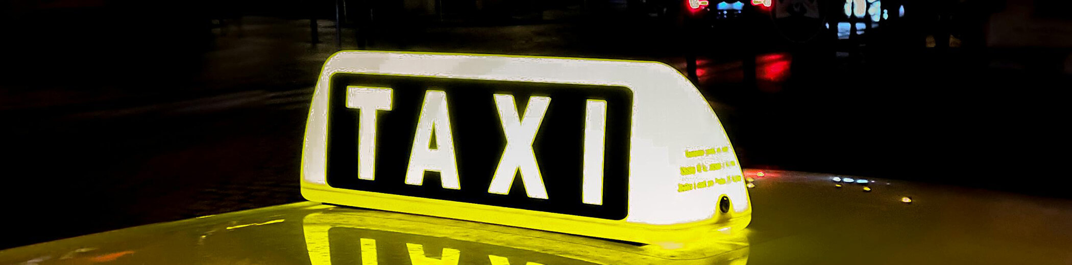 ein leuchtendes Taxischild auf einem Fahrzeug bei Nacht