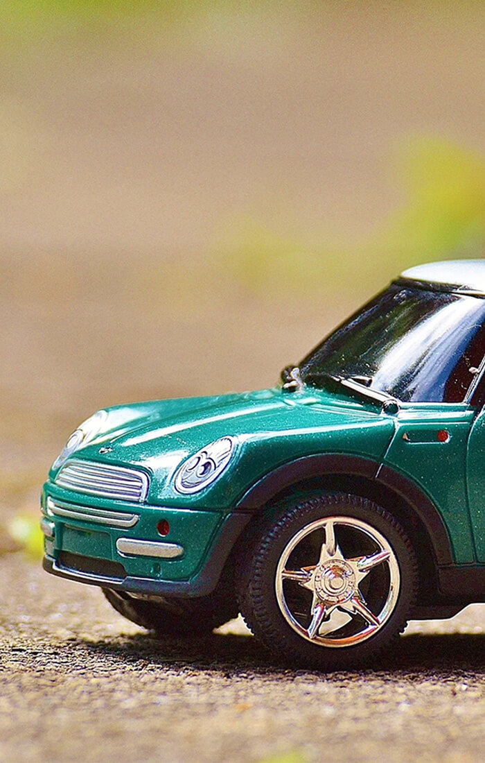 kleines Spielzeug-Modell eines Mini steht auf dem Asphalt