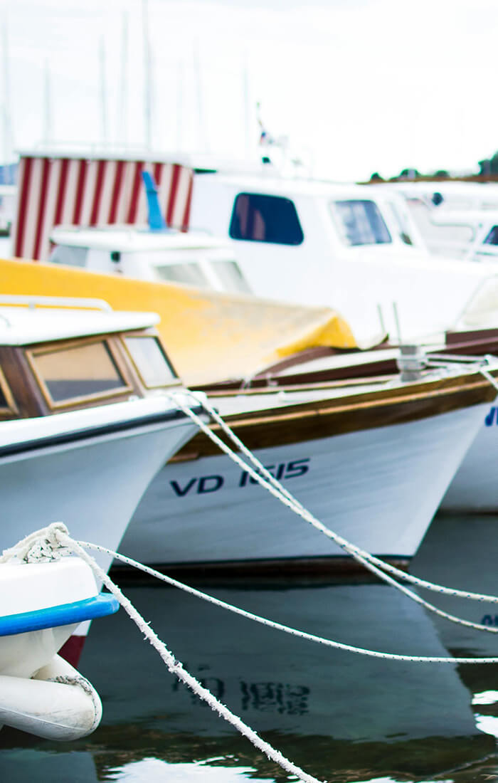Mehrere kleine Boote, die in einem Hafen vor Anker liegen und mit Seilen festgemacht sind